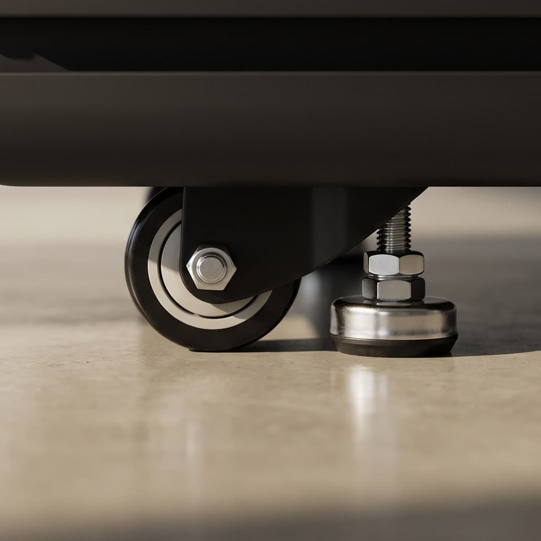 A close-up of the base of a Peacepod on a polished concrete floor — a swivel caster alongside an adjustable levelling foot beneath the pod's base plinth