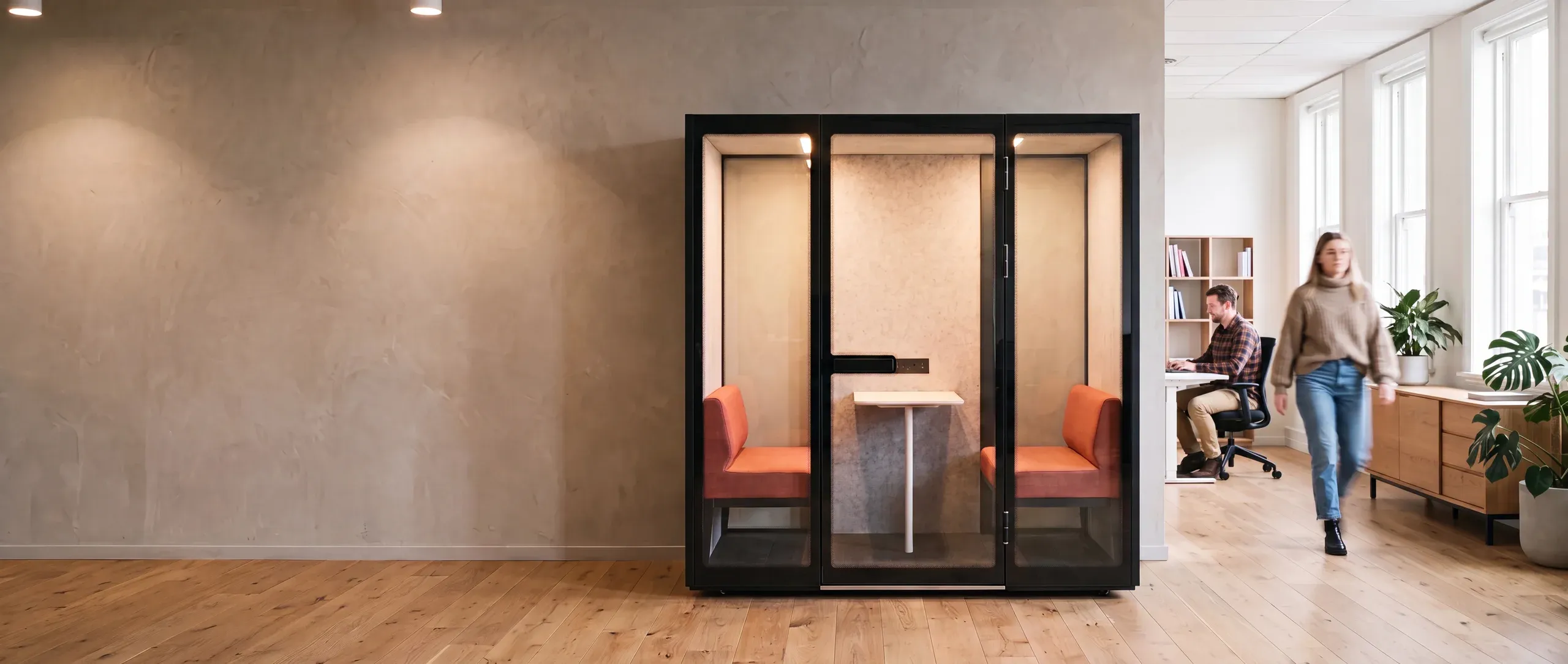A Peacepod meeting pod with facing bench seats and a table, in an open-plan office